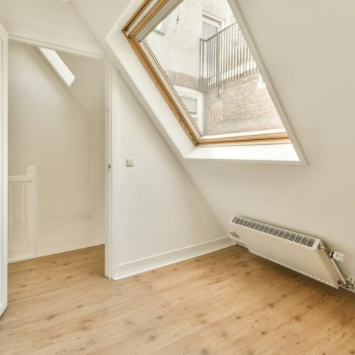 a loft conversion with a window and a wooden floor