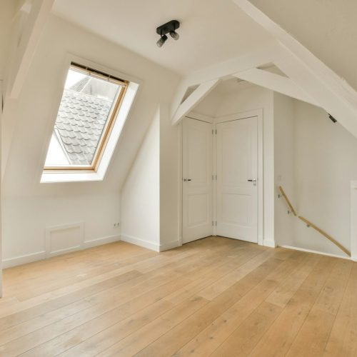 a loft conversion with white walls and wooden flooring