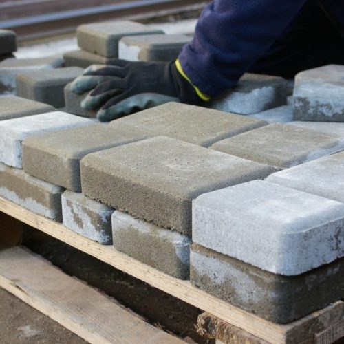 paver master. Man lays paving stones in layers. Garden brick pathway paving by professional worker.