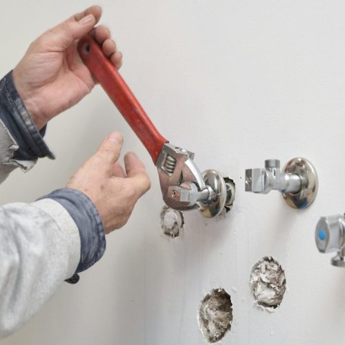 Plumber screwing plumbing fittings with an adjustable wrench.